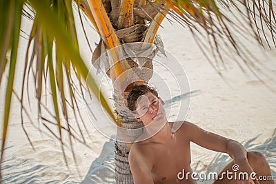 Handsome young tanned man relaxing at the beach at the tropical island luxury resort Stock Photo