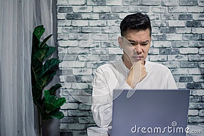 Handsome young thinking while serious working at home with laptop on desk Stock Photo