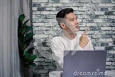 Handsome young thinking while serious working at home with laptop on desk Stock Photo