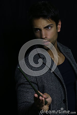 Handsome young wizard holding a magic wand Stock Photo