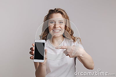 Handsopme young woman holding white iphone isolated over the white background Stock Photo