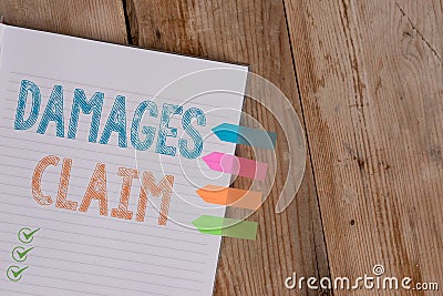 Handwriting text writing Damages Claim. Concept meaning Deanalysisd Compensation Litigate Insurance File Suit Striped note book Stock Photo