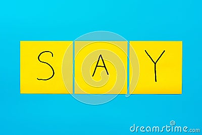 Handwritten black inscription say on yellow square stickers on a blue background close-up, horizontal orientation Stock Photo