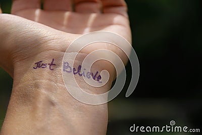 Handwritten motivational phrase on the hand `Just believe` Stock Photo