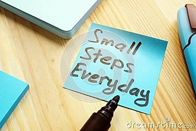 Handwritten quote Small steps everyday on table. Stock Photo