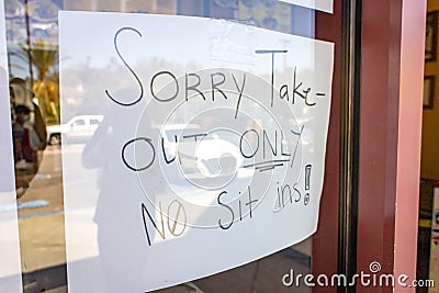 Handwritten sign at restaurant stating Sorry Take-Out Only No Sit Ins due to coronavirus pandemic Stock Photo