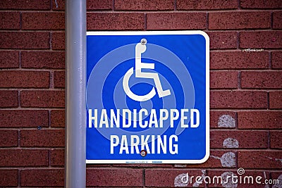 Handycapped Parking sign on brick wall with pipe Editorial Stock Photo