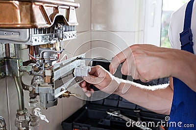 Handyman adjusting gas water heater Stock Photo