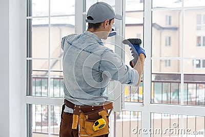 handyman adjusting white pvc plastic window indoors. worker using screwdriver to repair upvc window. homework Stock Photo