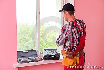 handyman adjusting white pvc plastic window indoors. worker using screwdriver to repair upvc window. homework Stock Photo