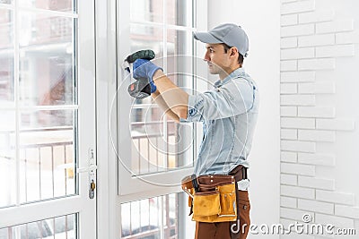 handyman adjusting white pvc plastic window indoors. worker using screwdriver to repair upvc window. homework Stock Photo