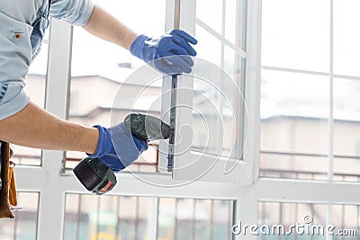 handyman adjusting white pvc plastic window indoors. worker using screwdriver to repair upvc window. homework Stock Photo