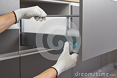 Handyman assembling and sets up a Drawer In the Kitchen. Worker fix the furniture mechanism of the Cabinet drawer Stock Photo