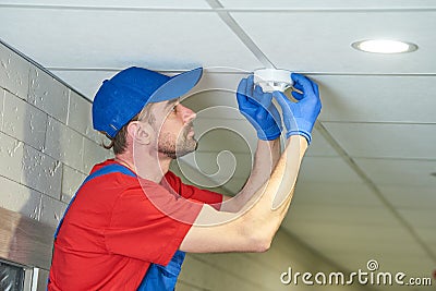 Worker installing smoke detector on the ceiling Stock Photo