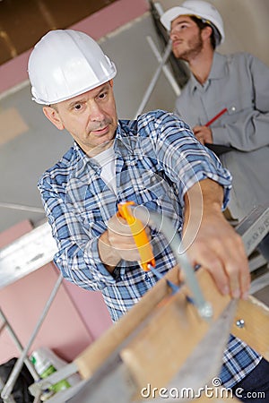 Handyman cutting wood with hand saw in garage Stock Photo