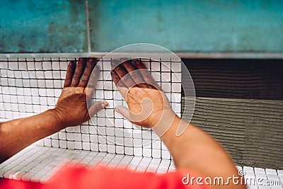 Handyman hands fixing and applying ceramic tiles on bathroom walls. Stock Photo