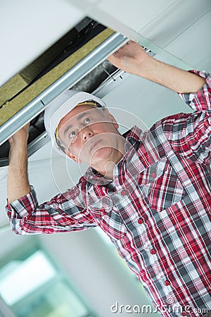 Handyman hiding cable in ceiling Stock Photo