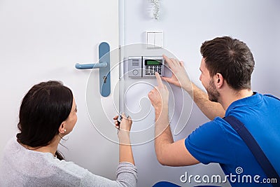 Handyman Installing Security System Near Door Wall Stock Photo