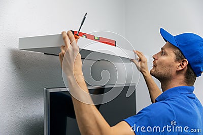 Handyman installing shelf on the wall Stock Photo