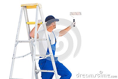 Handyman on ladder while using paint roller Stock Photo