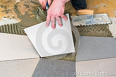 Handyman laying ceramic floor tiles Stock Photo