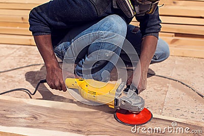 A handyman polishing wooden plank outdoor Stock Photo