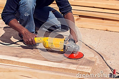 A handyman polishing wooden plank outdoor Stock Photo