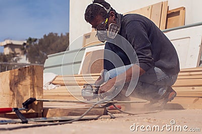 A handyman polishing wooden plank outdoor Stock Photo