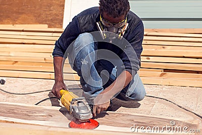 A handyman polishing wooden plank outdoor Stock Photo