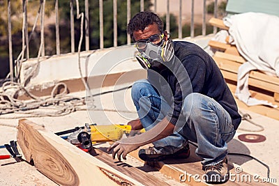 A handyman polishing wooden plank outdoor Stock Photo