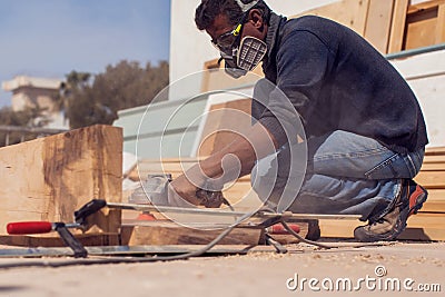 A handyman polishing wooden plank outdoor Stock Photo