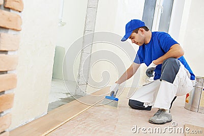 Parquet worker adding glue on floor Stock Photo