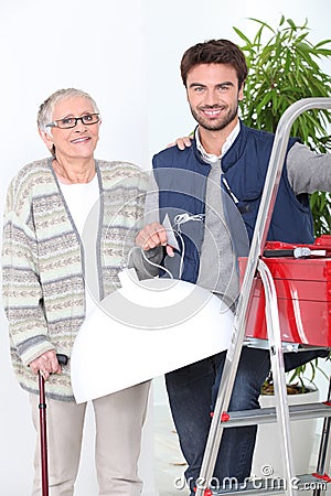 Handyman putting up lampshade Stock Photo