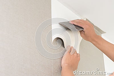 Handyman putting up wallpaper on the white walls Stock Photo