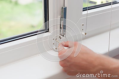 Handyman repairs plastic window with a hexagon. Workman adjusts the operation of the plastic window Stock Photo