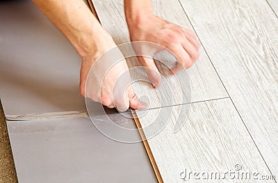 Handyman`s hands laying down laminate flooring boards Stock Photo