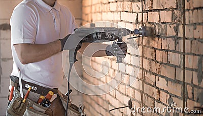 Handyman uses jackhammer, for installation, professional worker on the construction site. The concept of electrician and handyman Stock Photo