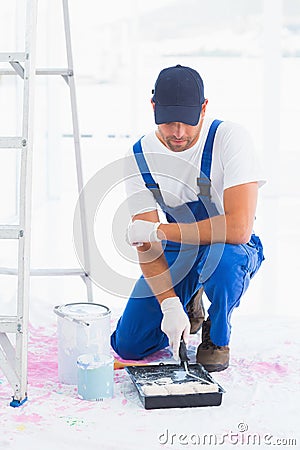 Handyman using paint roller in tray at home Stock Photo