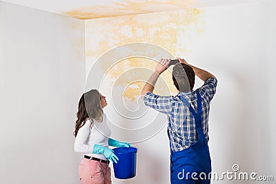 Handyman With Woman Photographing Ceiling At Home Stock Photo