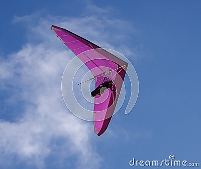 Hang glider flies by on purple wings with blue sky and wispy clouds above Editorial Stock Photo