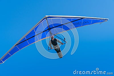 Hang glider pilot flying towards under bright blue wing and sky Editorial Stock Photo