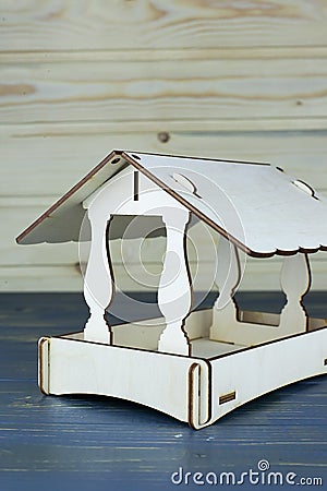 Hanged up old wooden manger with roof and seeds for small birds and nuts for squirrels at winter snowbound city park. Stock Photo