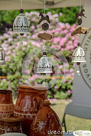 Hanging delicate handmade ceramic bells and some pots in the background Editorial Stock Photo