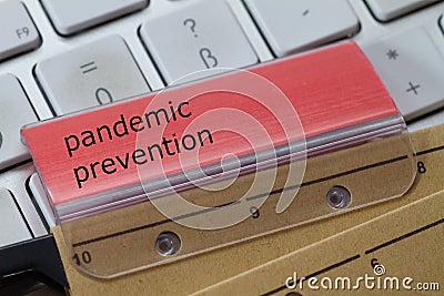 Hanging folder with red tab on which pandemic prevention is noted. A keyboard in the background Stock Photo