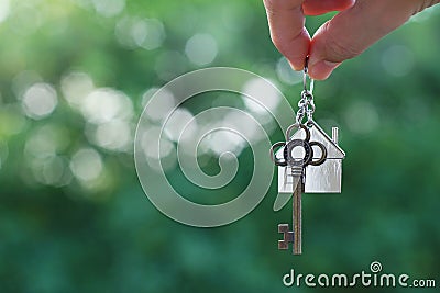 Hanging home key with house keyring with green garden background Stock Photo