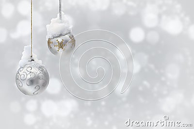 Hanging silver christmas balls covered snow on a blur light background with space for text Stock Photo