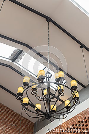 Hanging vintage black Chandelier ceiling with yellow lamp and brick wall interior Stock Photo