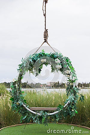 Hanging vintage wooden swing decorated with flowers and leaf. The design for decor place at outdoor Stock Photo