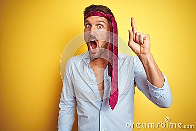 Hangover business man drunk and crazy for hangover wearing tie on head pointing finger up with successful idea Stock Photo