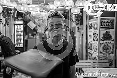 Hanoi, Vietnam - April 17, 2018: Waiter spins menu and smiles at camera in Bia Hoi corner of Hanoi. Editorial Stock Photo